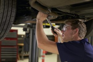 Auto Mechanic Working Underneath Car In Garage